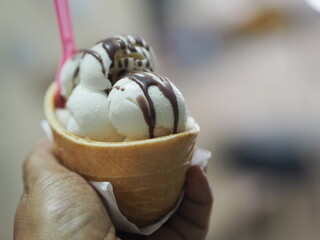 Coconut milk ice cream in a crispy waffle cup in woman hand