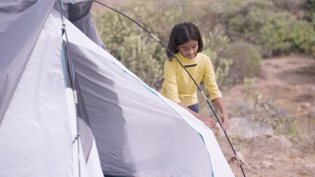 teengaer girl kid busy removing camping tent after staying - concept of training, outdoor activities and summer camp.