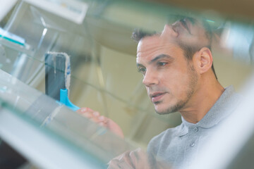 reflected view of man cleaning glass louver window
