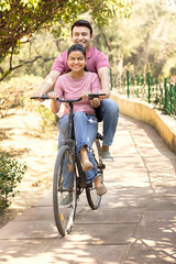 Naklejka premium Beautiful indian couple riding bicycle together in park