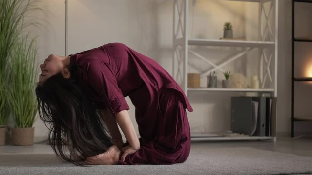 Yoga lifestyle. Healthy habit. Sporty leisure. Calm flexible young woman practicing camel pose stretching backbend exercise at home.