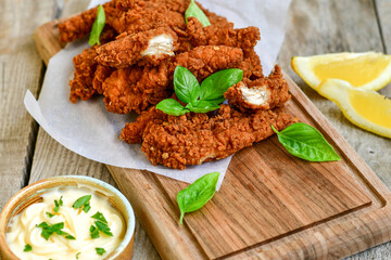 
 Crispy  deep Fried   Chicken strips and wedges potato. Breaded  with cornflakes chicken  Breast Fillets  with chilly peppers and fresh   basil on wooden rustic background