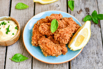 
 Crispy  deep Fried   Chicken strips and wedges potato. Breaded  with cornflakes chicken  Breast Fillets  with chilly peppers and fresh   basil on wooden rustic background