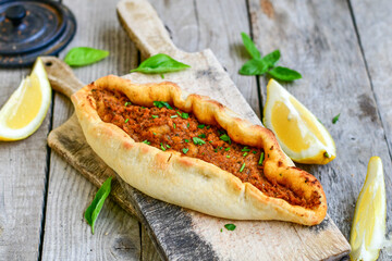  Traditional Turkish cuisine. Baked Pide dish with minced  beef, tomatoes and  herbs on  wooden background.  Turkish pizza pide