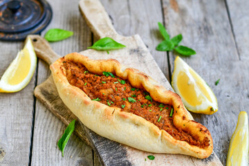  Traditional Turkish cuisine. Baked Pide dish with minced  beef, tomatoes and  herbs on  wooden background.  Turkish pizza pide