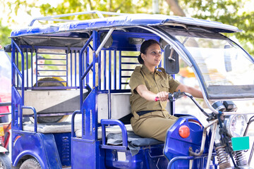 Portrait of happy woman in uniform driving six seater electric rickshaw