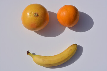 smiling orange, grapefruit and banana on white background