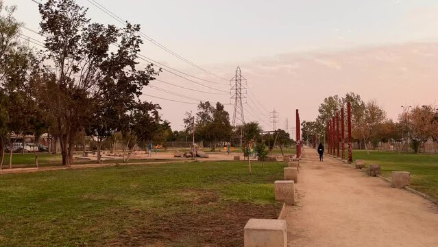woman walking quietly along a park path on a cloudy autumn day in Santiago, Chile