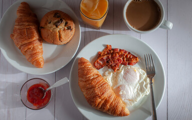 Breakfast with overmedium eggs, bacon , bread orange juice and cream coffee on a white table, top view or overhead shot panoramic