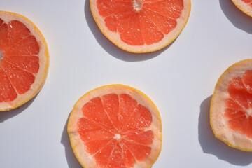 Colorful fruit pattern of fresh grapefruit slices on white background. Minimal flat lay concept.