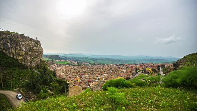 Time lapse shot of idyllic view from Chiesa Maria SS del Malpasso on Corleone Town during dense clouds at sky - Silhouette of mountain range in background