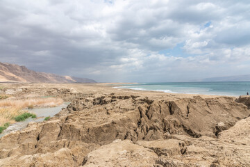 Exotic view of the sinkhole area of the Dead Sea on a stormy winter day. PhotoStorm and rain at the Dead Sea coastline. Salt crystals at sunset. The texture of the Dead sea. Salty seashore. High