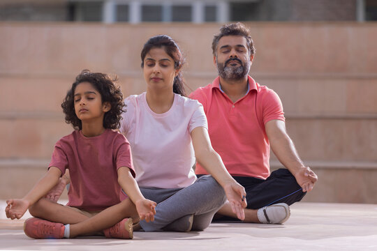 Portrait of happy family meditating together at outdoor in the morning