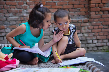 Portrait of little children studying on cot in the backyard