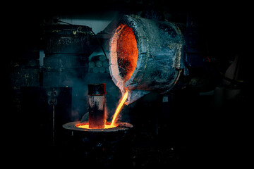 Foundry production. A ladle with molten metal. Pouring hot liquid metal into special molds. Close-up