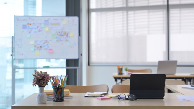 Startup business office interior with tables, laptop computers, chairs and whiteboard.