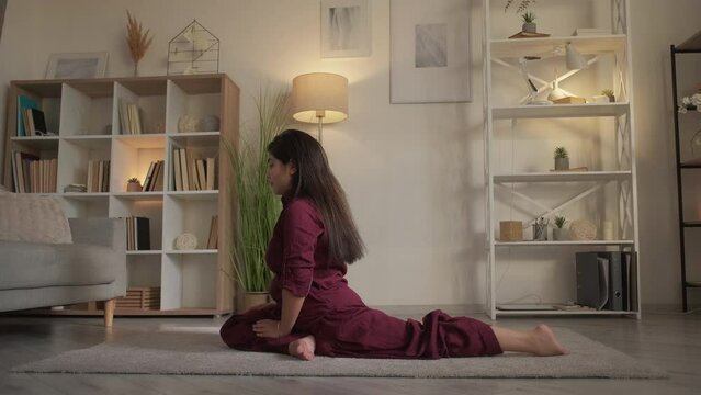 Yoga stretching. Flexibility exercise. Active hobby. Indoor training. Mindful woman practicing leg-split workout pigeon pose at home living room.