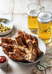 Smoked ribs on a platter, beer, bottle opener, sauce and olives. Party composition