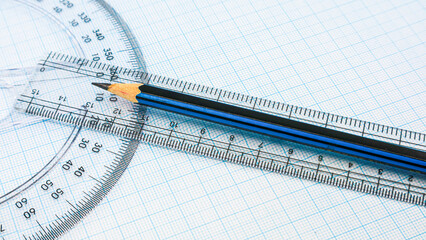 On blue graph paper are compasses, protractor, ruler, and a pencil