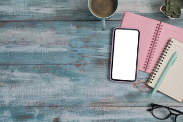 Mobile phone, notebooks, coffee cup and glasses on wooden background. Flat lay.
