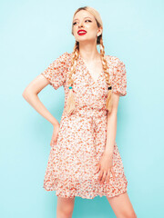 Young beautiful smiling female in trendy summer dress. Sexy carefree blond  woman posing near blue wall in studio. Positive model having fun. Cheerful and happy