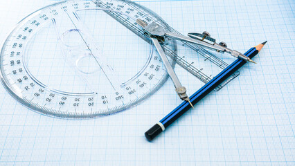 On blue graph paper are compasses, protractor, ruler, and a pencil