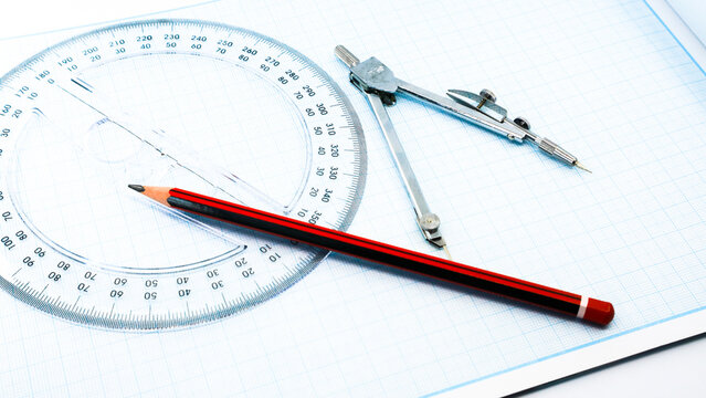 On blue graph paper are compasses, protractor, ruler, and a pencil