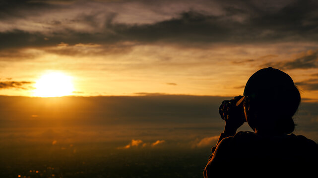 silhouette of  woman taking picture with camera at sunrise on DOI SUTHEP mountain viewpoint, chiang mai, Thailand
