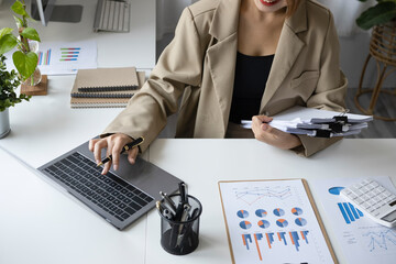 Female finance manager using computer laptop on white office desk.