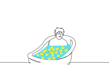 man is sitting in full bath and yellow rubber ducks are floating there - one line drawing vector. concept sad adult man taking a bath nostalgic for childhood