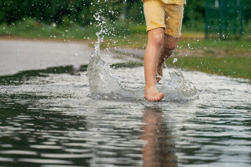 A cheerful girl runs through the puddles after the rain on a warm day