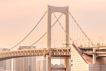 Rainbow Bridge, the most famous bridge in Tokyo and Odaiba area illuminated by warm sunlight during the sunset.