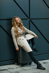 Obraz premium Young beautiful blonde woman with long hair with a suitcase near the airport terminal