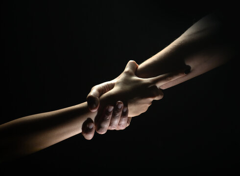 Two trength ands. Helping hand to a friend. Rescue or helping gesture of hands. Concept of salvation. Hands of two power people at the time of rescue, help. Isolated on black background.