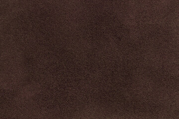 Background of dark brown suede matte fabric. Velvet matt texture of umber nubuck textile. Velveteen pattern.