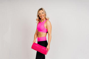 Fototapeta premium European girl is engaged in fitness on the mat. Self-massage of the muscles on a massage roller.