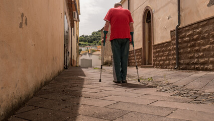 an happy elderly man walking down the street and alleys on crutches, doing rehabilitation