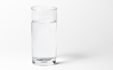 A clean glass transparent glass with water on a white background with a shadow. Side view and a little from above