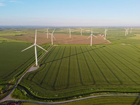 Aerial drone. Wind farm in the fields in south east England. Wind turbines near Camber Sands and Rye, East Sussex.