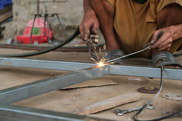 A male welder is making a steel frame construction