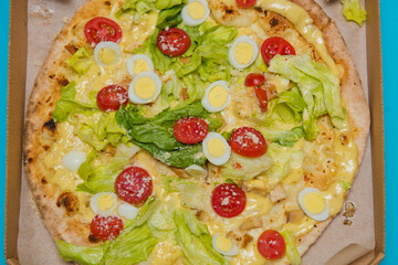 Delicious hot pizza in cardboard box on light blue background. Selective focus. Top view.