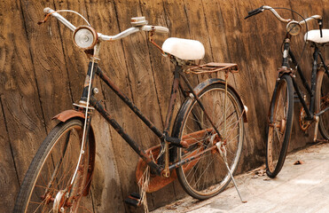 Fototapeta na wymiar Two old vintage bicycles rusted near a concrete wall.