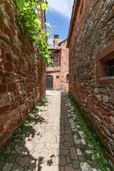 Fototapeta na wymiar Narrowest cobblestone back street of  Collonges-la-Rouge squeezed between 2 masonry walls. Correze department, New Aquitaine region, France