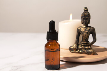 Spa treatment bottle of natural organic oil essence serum collagen. Aromatherapy and beauty concept. Aroma bottle with essential oils and Buddha on white background. Copy space for text.