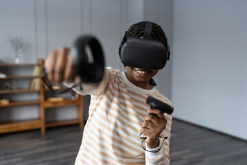 Young excited African American woman wearing vr glasses hold remote joystick first experience of...