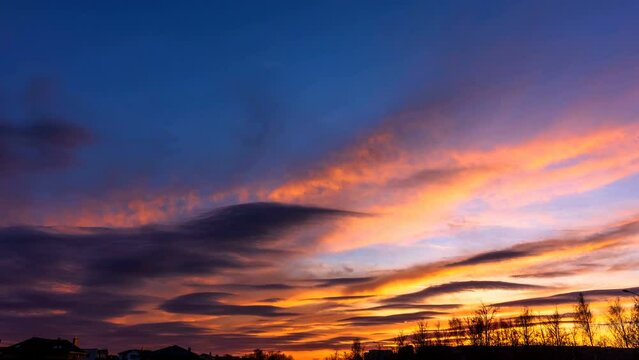 Time lapse a spring evening sunset with clouds of various shapes and colors