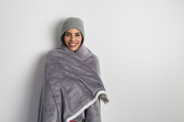 Smiling ethnic woman in warm blanket and hat