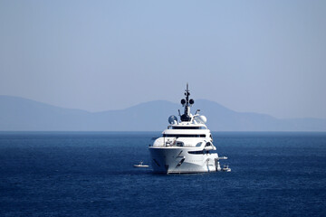 Luxury yacht with helipad and helicopter sailing in a sea, front view. White boat on mountain...