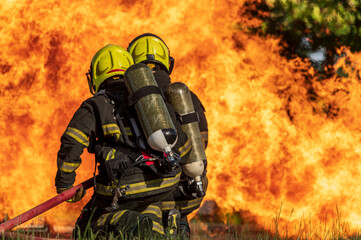 firefighters wearing fire fighter suit for safety and using twirl water extinguisher for fighting...