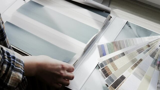 Woman fliping through catalog with roller blinds or window shade. Duo window roller system day and night. Choice of roller blinds.